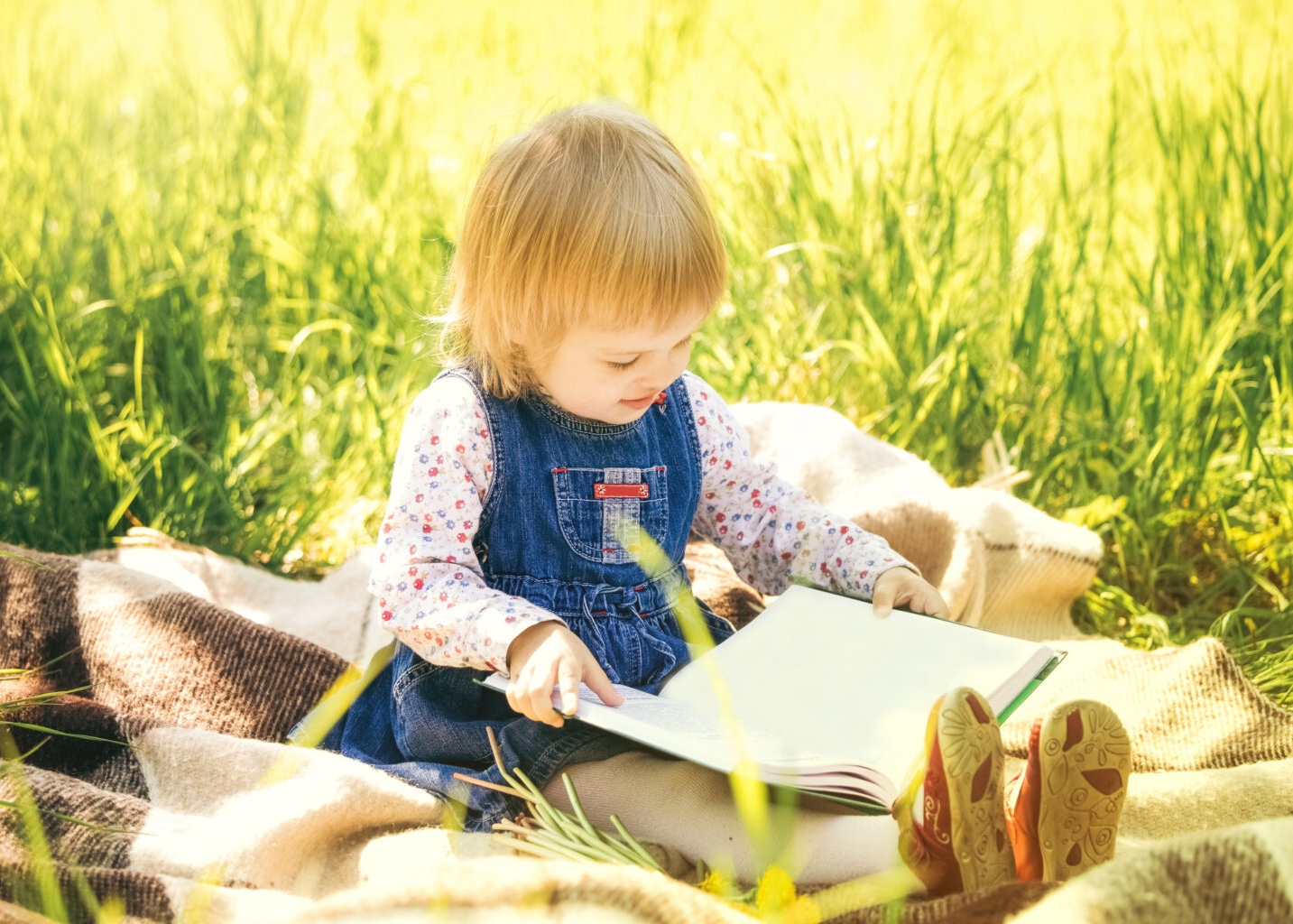Child reading book in park.