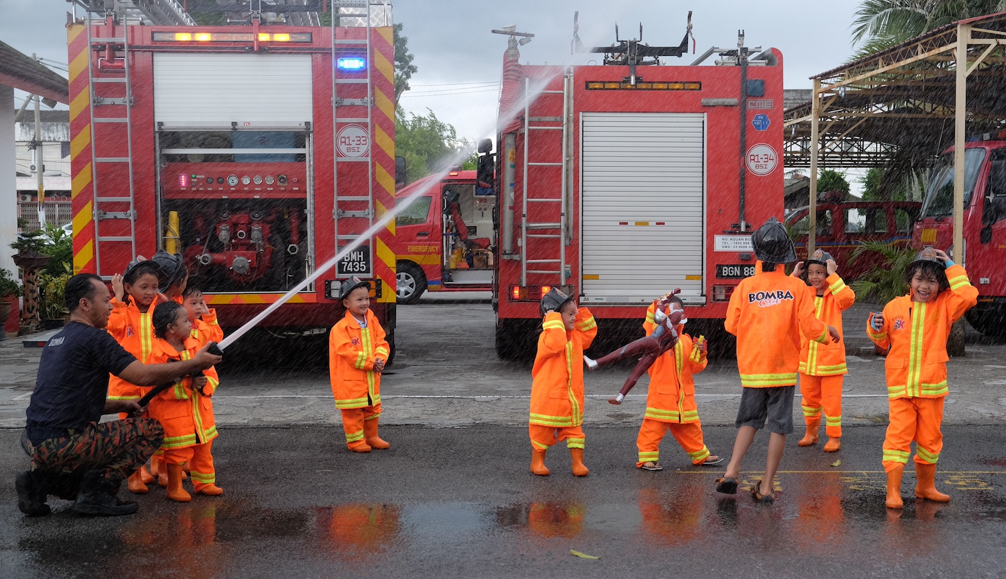Kids from pre-school dressed in fire fighter gear, attending fire fighting course.