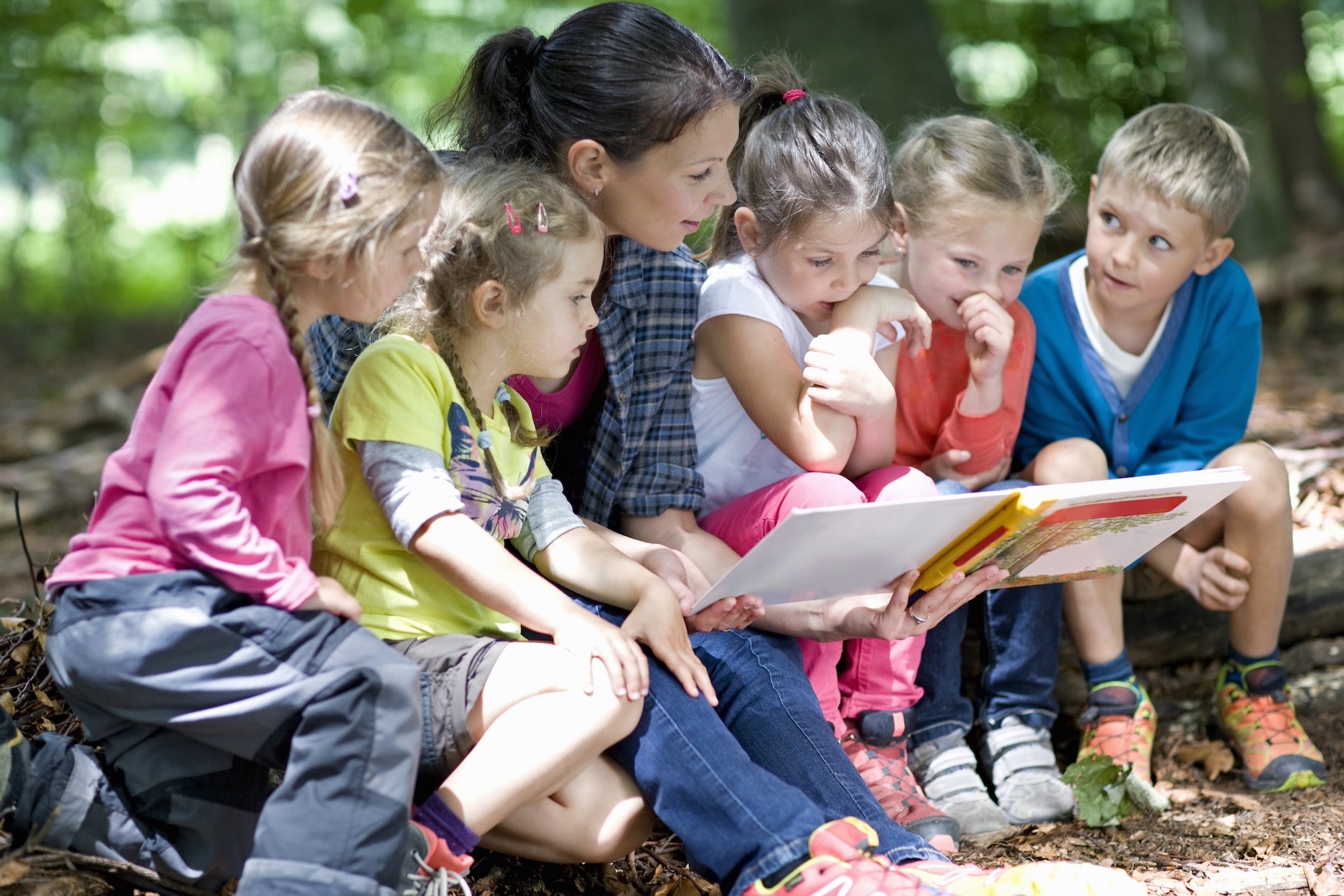 Kindergarten teacher reading with kids in a wood kindergarten